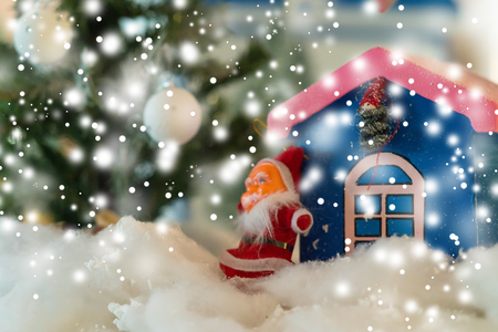 Santa Christmas ornament in a snowfall standing outside a colorful blue house with copy space for your greetingの写真素材