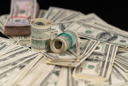Financial or cash background with USD bills scattered on a table, tied in rolls and wads with...