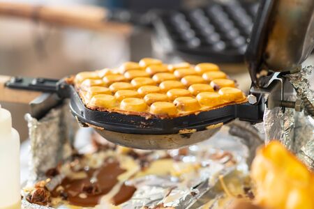 Tightly packed burgers filled with pulled meat on crusty rolls toasting on a griddle on a catering table at an eventの写真素材