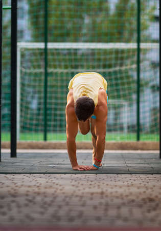 Low angle ground level view of a muscular man working out at an outdoor sports facility in a health...
