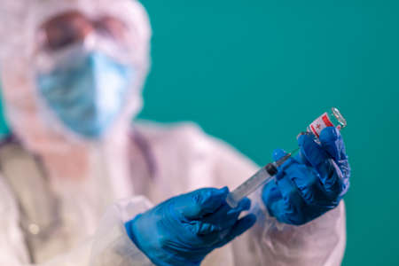 Doctor's hand in blue nitrile gloves holding vaccine shot for diseases outbreak vaccination