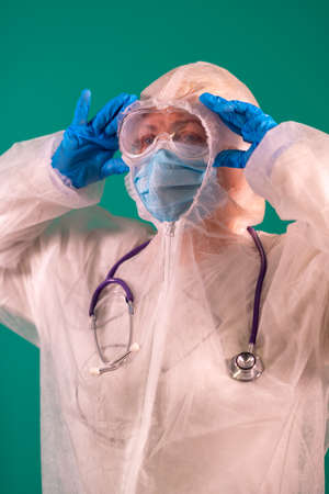 Female doctor in PPE suit uniform with stethoscope on the shoulder, wearing medical protective Mask and glasses on the faceの写真素材