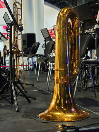 Shiny brass trombone standing on a stage floor with a backdrop of the equipment of the band in a low...