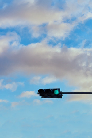A traffic signal gives a signal against the background of a bright cloudy skyの写真素材