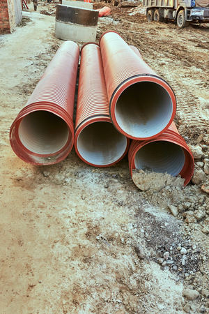 Red underground pipes lie on the ground before layingの写真素材