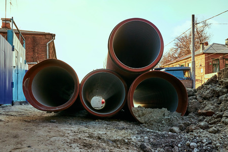 Red underground pipes lie on the ground before layingの写真素材