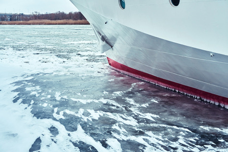 A white blue passenger ship anchored in a frozen river covered with ice and snowの写真素材