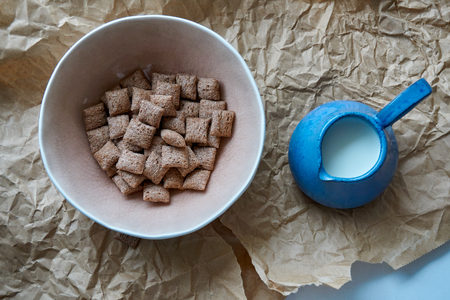 Dry breakfast is poured with milk into plates from a jug for milkの写真素材