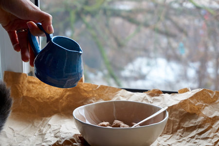 Dry breakfast is poured with milk into plates from a jug for milkの写真素材