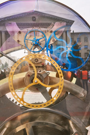 The internal mechanism of a large street clock through a glass window
