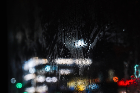 Through the misted glass in the bus video the night city with bright lights and carsの写真素材