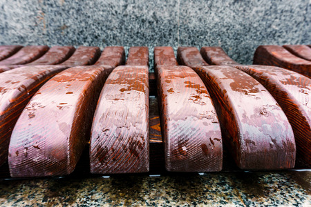 Wooden bench wavy form with puddles after the rain on the street close up
