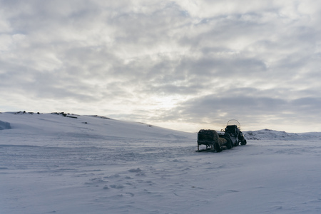 An empty snowmobile with a sleigh on a snowy hill against the background of a winter frosty skyの写真素材
