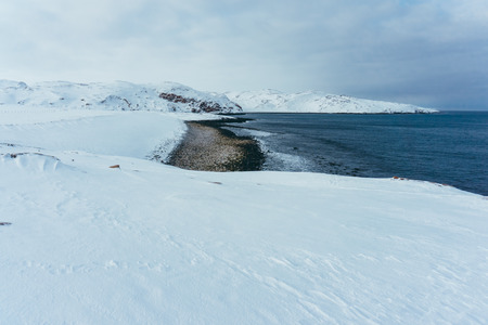 The shore of the northern ocean is covered with ice on a winter frosty day during the expeditionの写真素材
