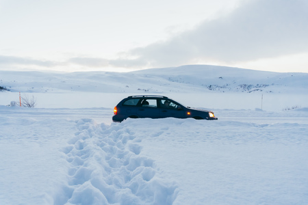 Blue car on a snow-covered road after a long snowfall a lot of snowの写真素材