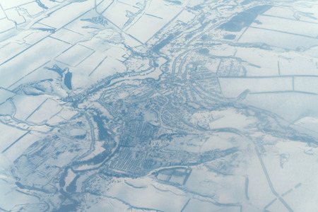 View of the city under the snow from the side of the plane flying high in the airの写真素材