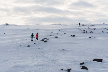 Two young girls in bright jackets travel on snowy peaks of the tundra in winter in a frost drowning in the snowの写真素材