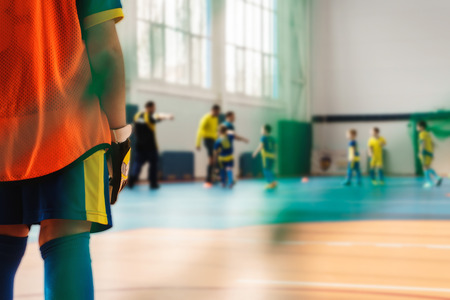 The young goalkeeper stands with his back and protects the goal from the opponent's balls in the closed sports complexの写真素材