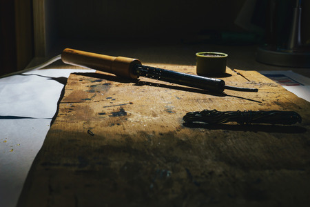 Working with a hot metal soldering iron at home under the spotlight and smoke that comes from liquid rosinの写真素材