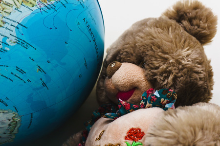 Soft plush toys and the globe of planet Earth lie on the shelf in a school for young childrenの写真素材