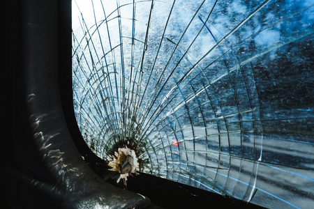 Broken glass from behind the hole in the city bus pasted with adhesive tape