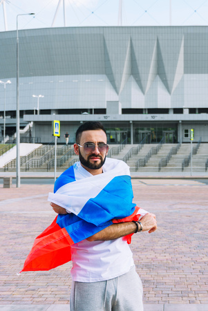 A young guy with a beard in his white T-shirt and shorts is holding a flag of Russia that is developing in the windのeditorial素材