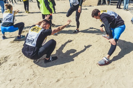 Rostov-on-Don / Russia - April 2018: Organized team run with obstacles in rough terrain with wooden structures on sandのeditorial素材