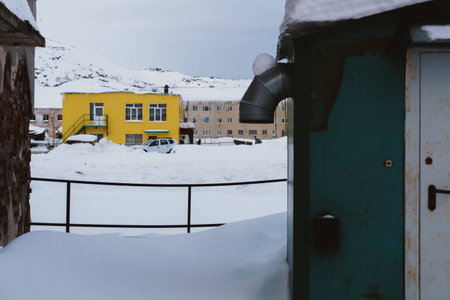 Old dilapidated and partially destroyed houses in which people still live in the village in the far north in winter under the thick slime of white snowの写真素材