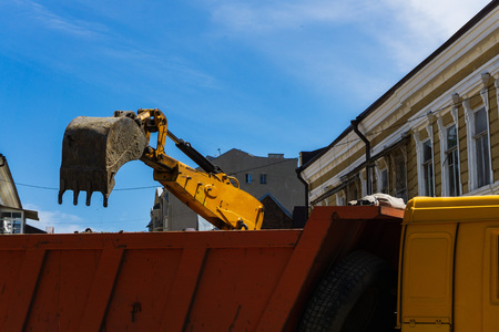 Powerful yellow excavators working on the reconstruction of a street in a big city