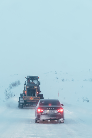 Teriberka, Murmansk region / Russia - February 2018: An automobile column moves along a snow-covered road during a blizzard and heavy snowfall behind a truck with a plowのeditorial素材