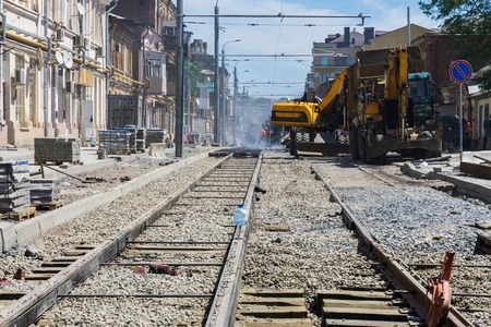 Laying of new steel rails on wooden sleepers in a prepared mound of large crushed stone for new tram lines in the city centerのeditorial素材