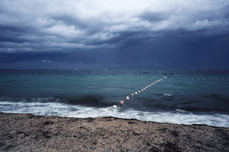 Lubricated small waves with foam during the beginning of the storm in the evening on the shore of...