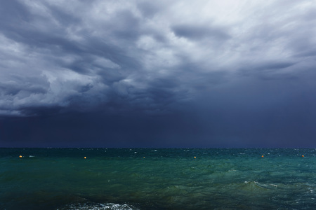 Small waves with foam at the time of storm beginning in the evening on the shore of the dark sea on...