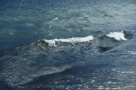 Small waves with foam at the time of storm beginning in the evening on the shore of the dark sea on the beach of the sea resortの写真素材