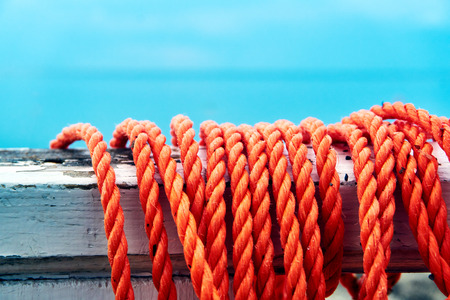 A strong red rope hangs on a wooden structure on the seashore and can be used to rescue drowning people by rescuersの写真素材