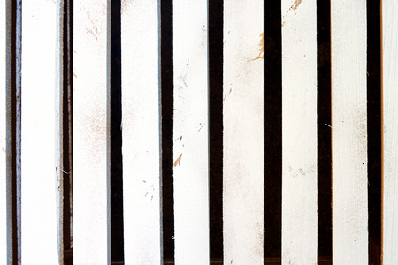 The wooden grill of white boards is lit by warm light on a hot sunny day at the cottageの写真素材