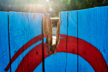 Vertical wooden planks of blue color in the fence around the village house photographed in a sunny...