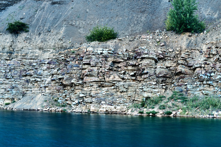 a sheer high wall in the gorge above the blue lake consisting of layers of minerals and rocks during...