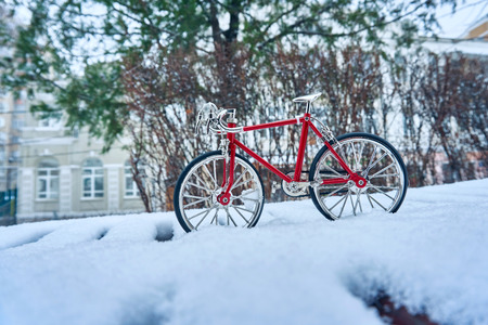 A toy model of a red bicycle made of metal, executed with good accuracy, is in winter in snowdrifts...