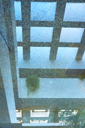 a reflection in the water of a square concrete geometric ceiling with a multitude of windows on top...