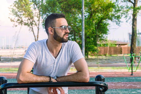 a young guy in good physical shape with a beard and in sunglasses trains on the simulators on the...