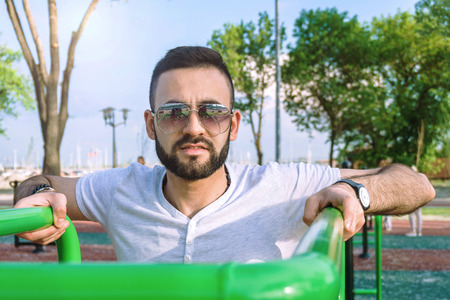 a young guy in good physical shape with a beard and in sunglasses trains on the simulators on the...