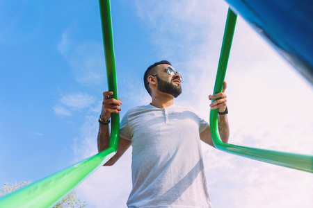 a young guy in good physical shape with a beard and in sunglasses trains on the simulators on the...