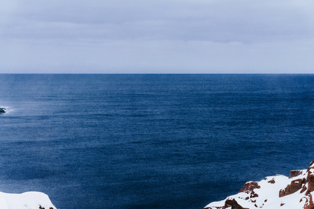 white snow on the rocky shore of the blue sea flowing into the northern ocean on a cold winter day north of the polar circleの写真素材