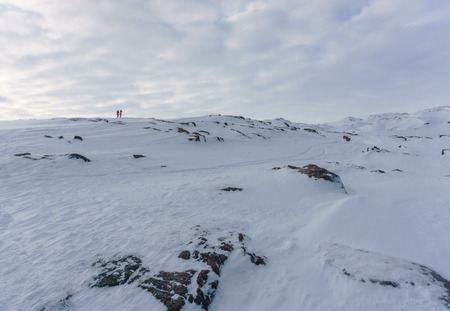 people in bright jackets go somewhere far along the snowy peaks of the tundra on a frosty winter day during a trip to the arcticの写真素材
