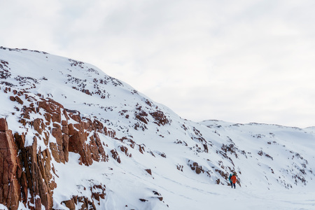 dangerous rocks of red on the ocean in the north of the Arctic Circle under the snow during the cold winter monthsの写真素材