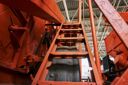 metal steps on the stairs leading to the cab of an old orange tractor tractor driver at an outdoor...