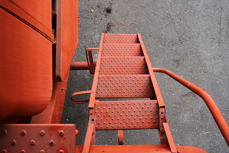 metal steps on the stairs leading to the cab of an old orange tractor tractor driver at an outdoor...