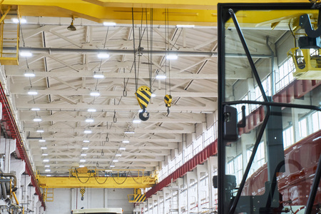 the ceiling of a large factory room after repair with artificial lighting and large yellow girder cranes on a bright dayの写真素材