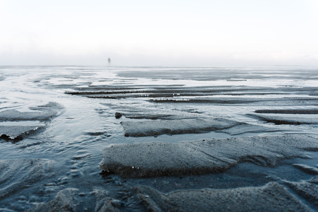 The outflow of water on the northern sea in winter shows the sand at the bottom that immediately...